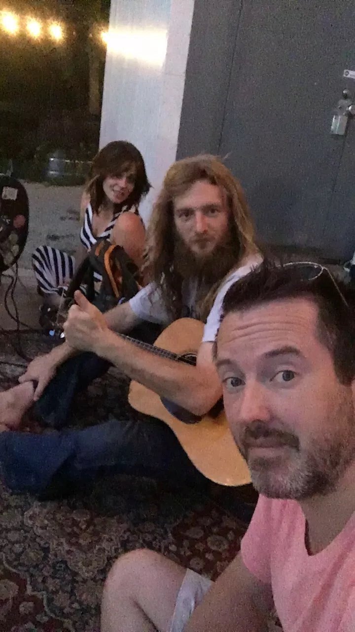 Three musicians picking under string lights